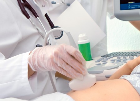 Ein Arzt untersucht den Bauch einer Frau mit einem Ultraschallgerät